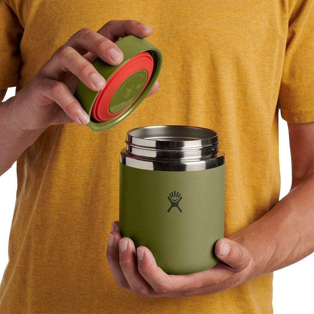 Olive green Hydro Flask insulated container with smooth matte finish, wide cylindrical shape, flat lid, brushed stainless-steel band at top, and logo on front.